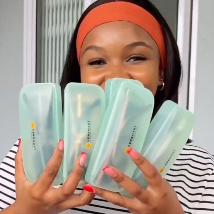 A smiling creator in an orange headband fans out five mint-green Lensmart glasses cases in front of her face