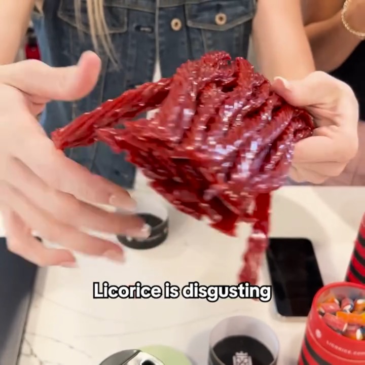 Hands pull apart a big bundle of red twisted licorice over a kitchen counter with licorice tubs, captioned “Licorice is disgusting”