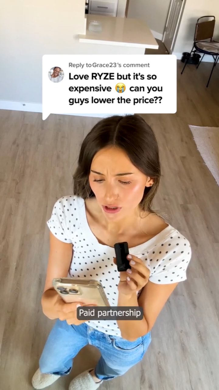 A woman in a polka-dot top frowns at her phone under a comment sticker reading “Love RYZE but it's so expensive 😭 can you guys lower the price??”, with a “Paid partnership” label