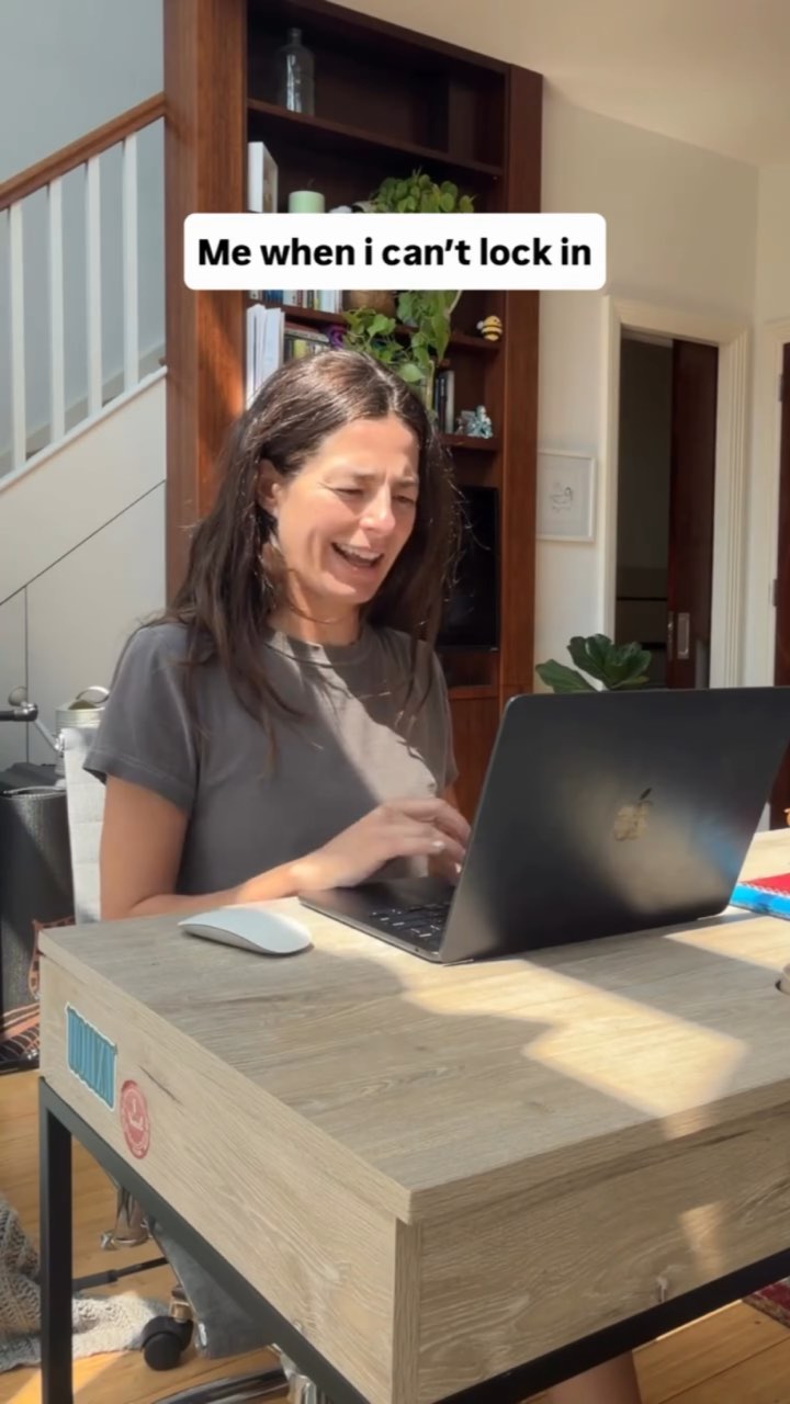 A woman at a sunlit home desk grimaces at her laptop under the caption “Me when i can’t lock in”