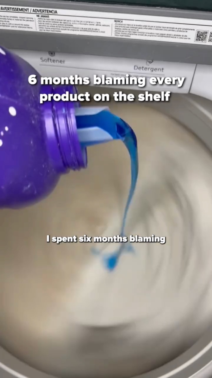 Blue liquid detergent pours from a purple jug into a spinning top-load washer drum, captioned “6 months blaming every product on the shelf” and subtitled “I spent six months blaming”